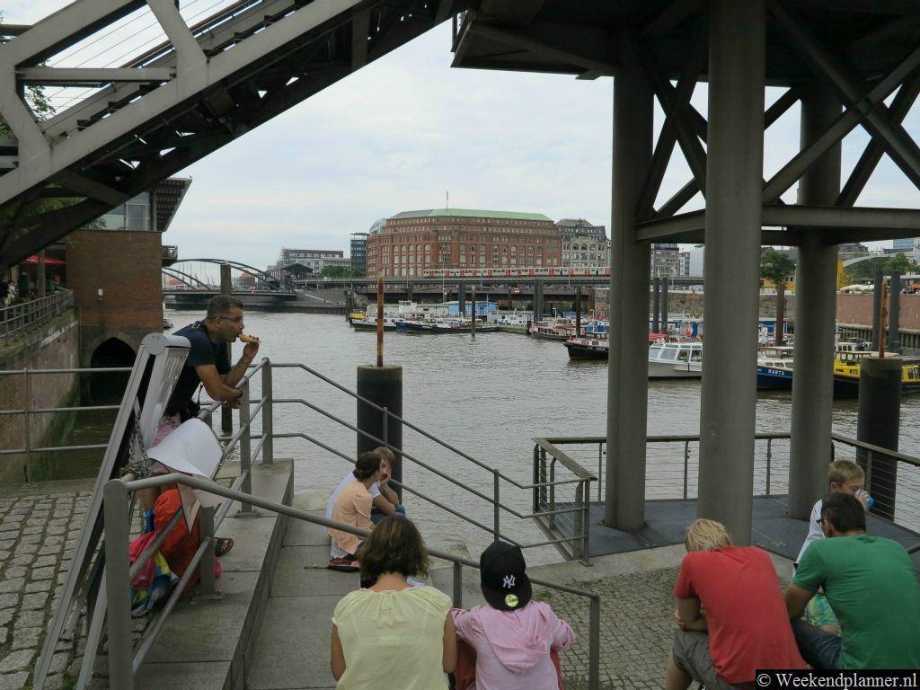 Uitzicht vanuit Speicherstadt op de rondvaartboten. Op de achtergrond rijdt de metro naar het metrostation Baumwall in de haven van Sankt Pauli.
